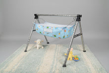 Load image into Gallery viewer, Baby crib with a blue sheet featuring cartoon characters on a white tiled floor.